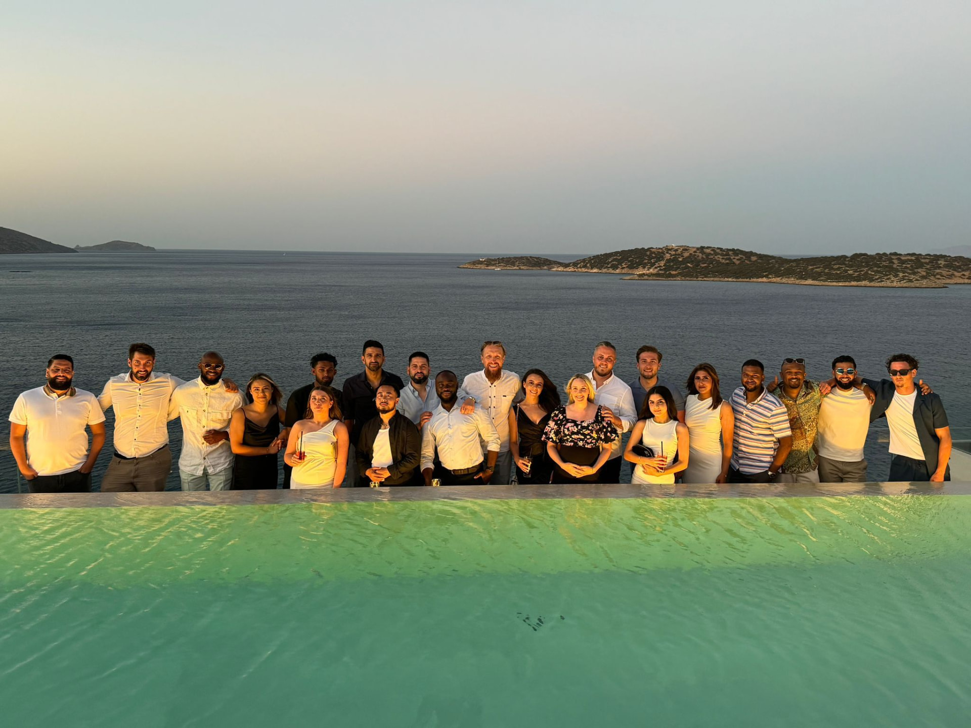 Sales Original team together beside a pool overlooking the sea